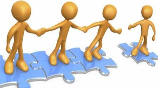 stick figures standing on joined puzzle pieces holding hands and reaching out to another figure on a separate puzzle piece
