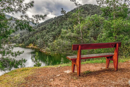 an unoccupied bench overlooking a river in a valley
