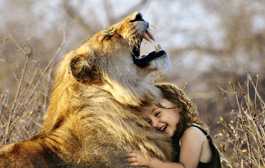 a young child hugging a lion who is roaring