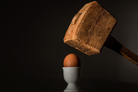 an egg under the aim of a hammer