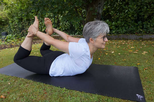 an older woman doing yoga outside