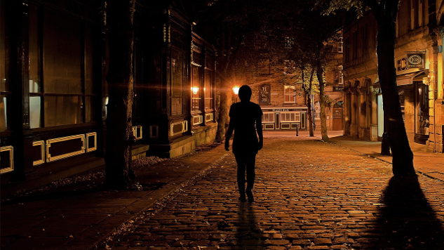 a lone figure walking on a dark street