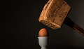 a hefty hammer being held over an egg
