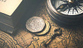 photo of a key, a compass, coins, overlayed on an old map
