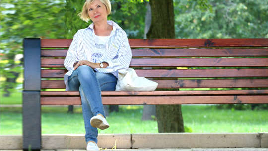 smiling woman seated on a public bench