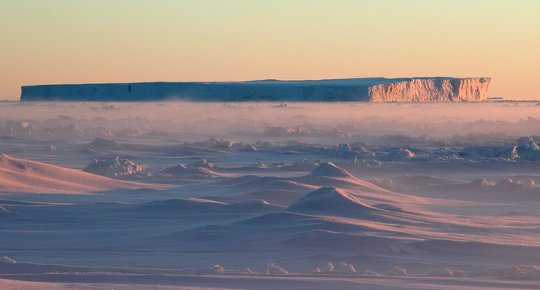 A tabular iceberg gets stuck in thin, seasonal sea ice.
