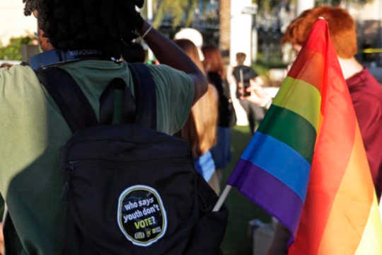 In this Oct. 31, 2018 photo, a student with a rainbow flag listens to speakers during a Vote for Our Lives rally at the University of Central Florida in Orlando, Fla. (why we should pay attention to the voting power of youth)