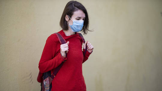 girl wearing a Covid mask outside carrying a backpack