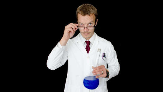 medical practitioner holding a beaker of blue liquid