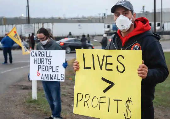 Protesters stand on the side of the road as workers return to the Cargill beef processing plant in High River, Alta.,