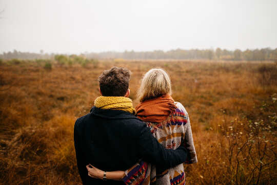 couple looking out at a bare grassy field