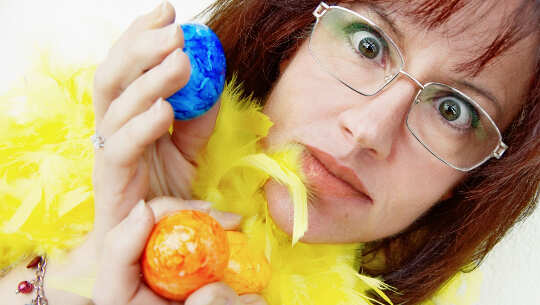 image of woman holding up two colored eggs... with a surprised look on her face