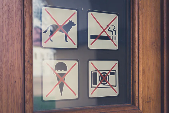 Sign on a door refusing dogs entry. Also no smoking, no cameras, and no ice cream.
