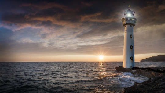 picture of a lighthouse illuminating a path on the water
