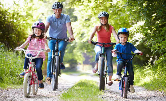 man, woman and two young children riding bicycles