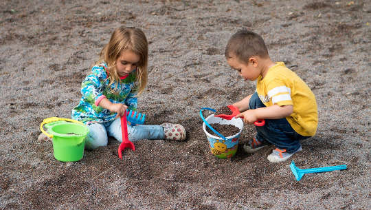 a young boy and girl playing in the sand