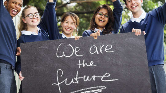 school kids holding up a sign that reads "We are the future"