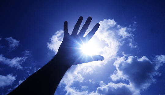open hand raised up to the sun and sky