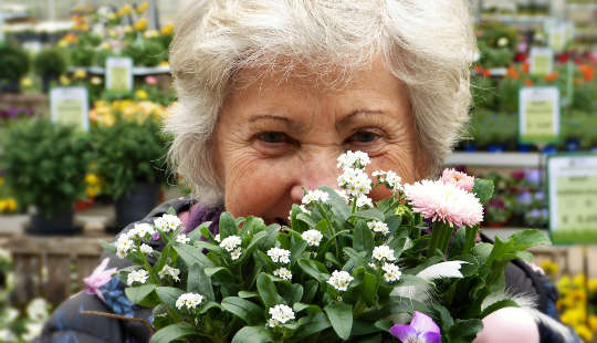 photo of an older woman with white hair behind a bouquet of flowers