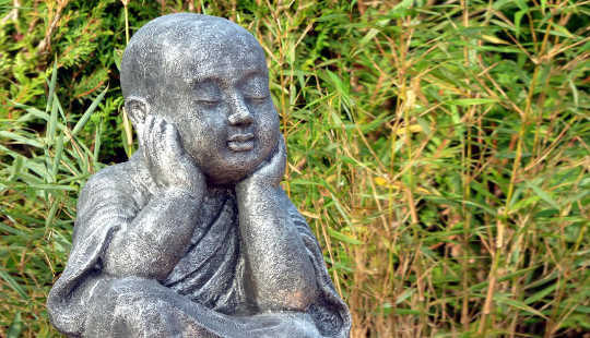 a statue of a sitting buddha in a field of grasses