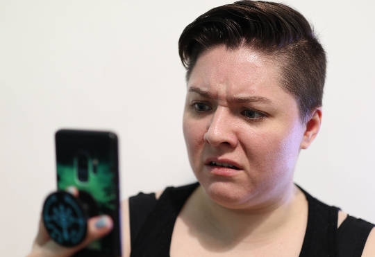 woman looking at her phone with a look of disgust on her face