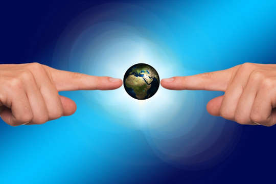 two hands pointing and touching planet earth