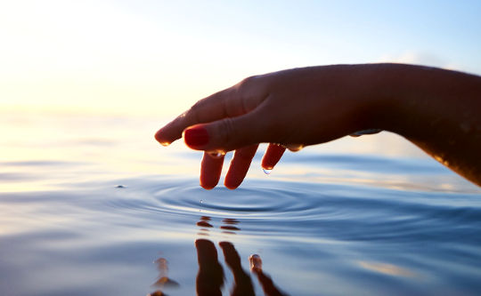 a hand making a ripple in the ocean