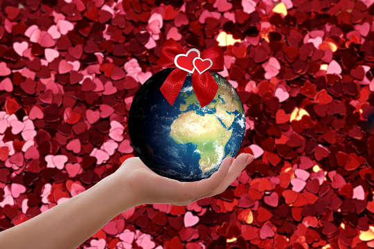 a hand holding Planet Earth surrounded by hearts