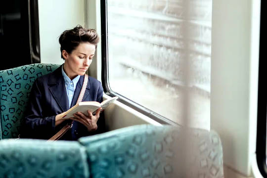 woman sitting in public transportation reading a book