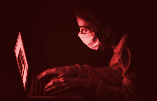 a person wearing a surgical mask working at a computer