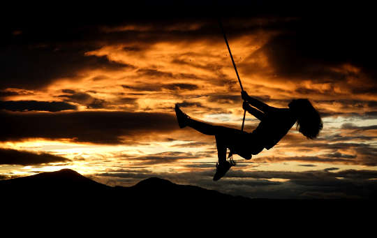 silhouette of a girl on a swing in front of the sunset