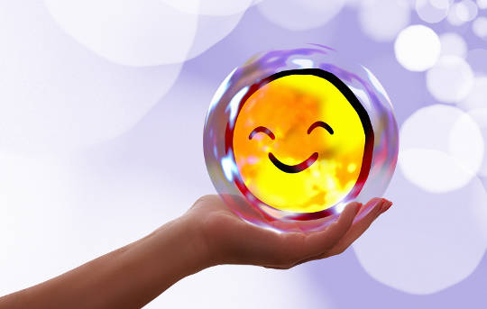 a hand holding a round smiling face image