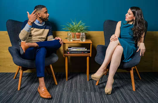 a man and woman sitting facing each other having a conversation