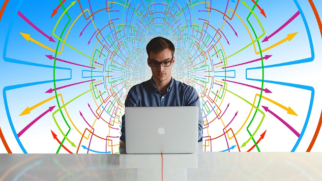 man sitting in front of a computer in front of a background of a busy chart and graph