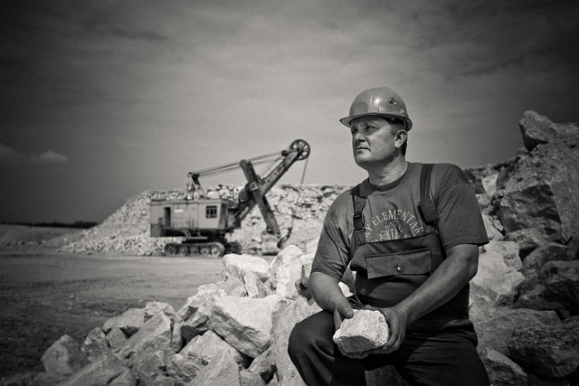 man sitting holding a big rock on a construction site