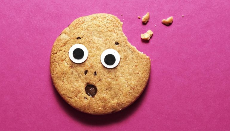 A surprised cookie with eyes and a mouth has one bite taken out it