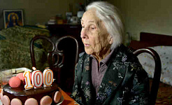 A 100-year-old woman blows out the candles on her birthday cake.
