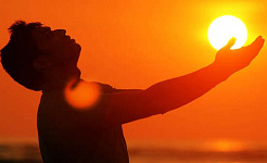 man outside with hands outstretched to the sun
