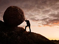 man pushing a boulder up a hill