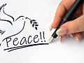 a hand writing the word Peace and drawing a dove holding an olive branch
