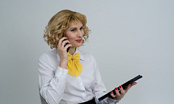 a business woman on the phone holding a tablet and smiling slightly