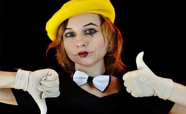 一个化着小丑般妆容的女人，做出竖起大拇指和向下的手势