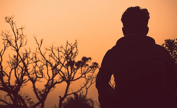 Мужчина стоит один на улице на закате