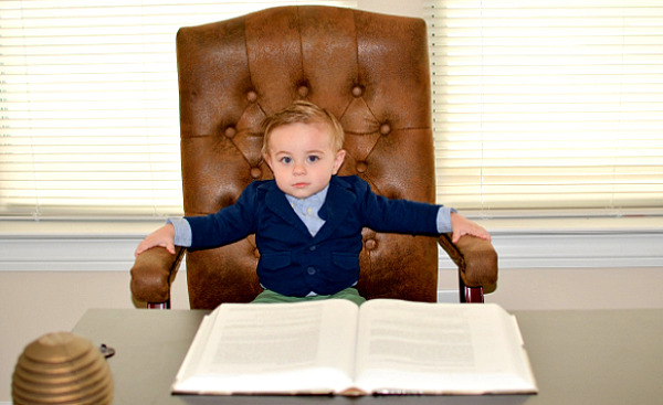 tânăr băiat așezat pe un scaun mare de piele în fața unui birou de afaceri
