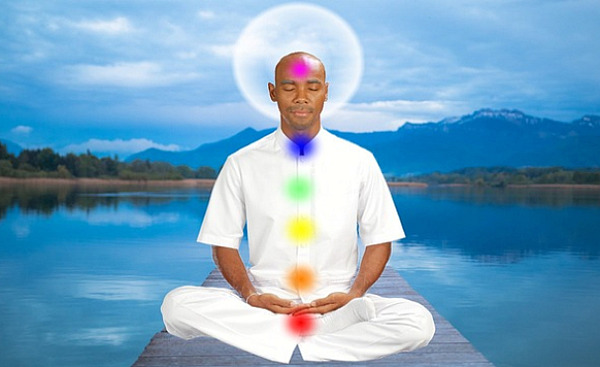 een man zit in meditatie met verlichte chakra's