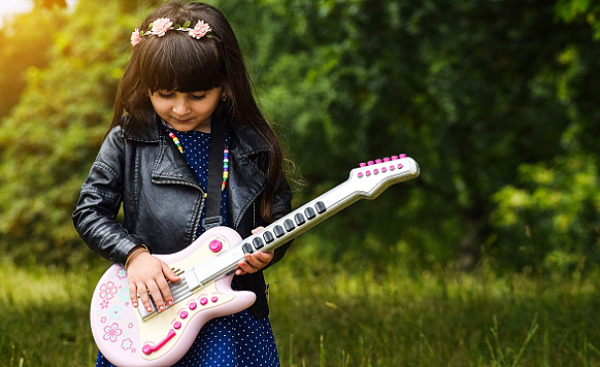 молодая девушка с цветами в волосах играет на электрогитаре