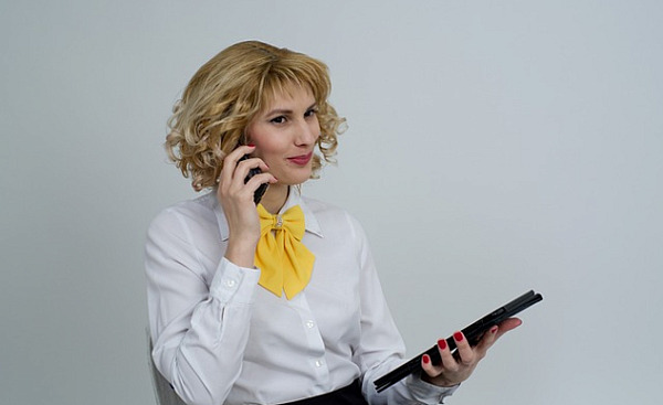 a business woman on the phone holding a tablet and smiling slightly