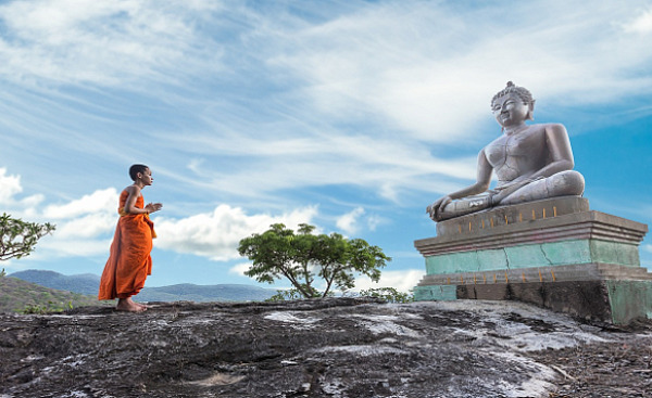 تمثال بوذا مع راهب شاب يقف أمامه