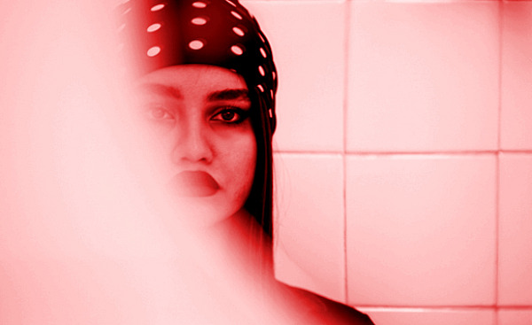 Una mujer joven en el espejo: la mitad de su rostro oculto en vapor.