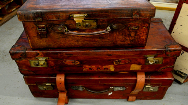 drei übereinander gestapelte, abgeschnallte alte Koffer